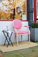 An upholstered Louis XVI-style chair with a pink-and-white striped jersey cover