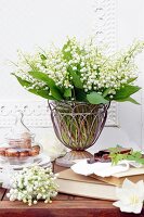 Bouquet of lily-of-the-valley in vintage metal and glass vase on table