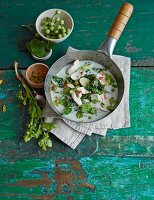 Green Thai curry with chicken breast fillet and kale in a pan