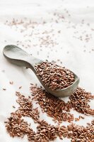 Flax seeds on a wooden spoon and on a white tablecloth