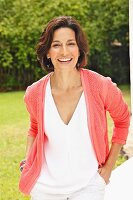 Dark-haired woman wearing top and cardigan in garden