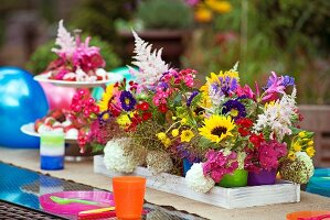 Colourful beakers of summer garden flowers decorating table