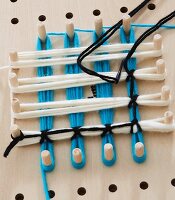 A pegboard with different coloured wool wrapped around the pegs