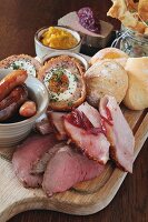 A ploughman's lunch featuring ham, sausages, Scotch eggs, chutney and bread rolls (England)