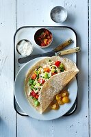 Burrito mit Fisch, Lauch, Paprika, Erbsen und Tomaten, dazu Tomatensalsa und Sauerrahm