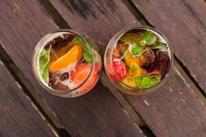 Two glasses of Pimms with fruit on a wooden table (seen from above)