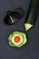 A spiral-cut cucumber shaped into a flower with a cherry tomato in the middle