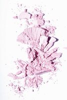 Rose-coloured eye shadow crumbled on a white surface