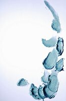 Lidschattencreme in Blaugrün verstrichen auf weißem Untergrund