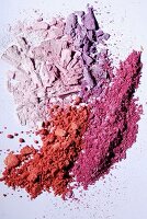Purple and red eye shadow crumbled on a white surface