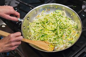 Glutenfreie Spaghetti mit Zucchinispaghetti in einer Pfanne auf dem Herd