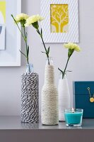 Yellow carnations in DIY vases made from bottles wrapped in twine
