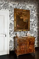 Antique, carved cabinet and framed painting on wallpaper with large botanical print