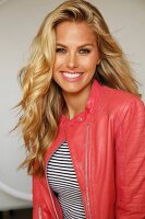 A blonde woman wearing a stripped shirt and a salmon-coloured leather jacket