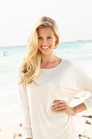 Junge blonde Frau in weißem Longshirt am Strand