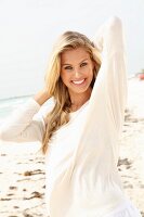 Junge blonde Frau in weißem Longshirt am Strand