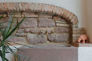 Stone sink with vintage tap fittings on rustic sandstone and brick wall