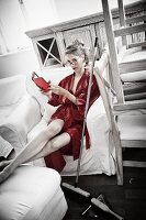 Junge Frau in rotem Kimono macht Pause beim Hausputz (Farben teils verfremdet)