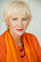 An older woman wearing an orange jumper and scarf