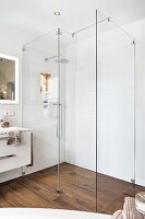 A walk-in shower with a glass partition wall and wooden-style floor tiles
