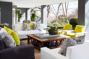 Covered terrace with seating area and colourful cushions with yellow accents