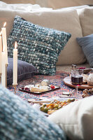 A picnic-style Christmas meal on a kilim rug with cushions and candles
