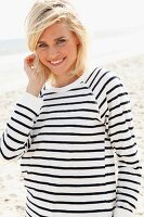A blonde woman on the beach wearing a black and white striped, long-sleeved T-shirt