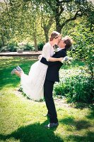 A young bride and groom kissing in a park