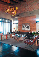 Wohnzimmer mit hoher Decke, skulpturalem Couchtisch und Lederstuhl