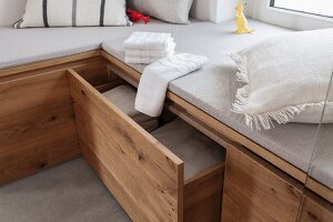 A made-to-measure, upholstered wooden corner bench with drawers for towels in a spa bathroom
