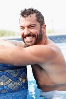 A dark-haired man with a beard in a pool