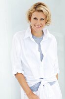 A blonde woman wearing a light-blue top and a white blouse