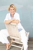 Blonde Frau sitzt rücklings auf Holzstuhl