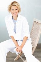 A blonde woman sitting on a wooden chair