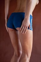 A woman wearing tight, blue, sporty shorts with her hands on her bottom