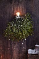 Sprigs of mistletoe with mother-of-pearl and a tea light as winter decorations
