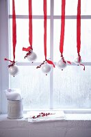 Weihnachtliche Fensterdeko mit rot-weiss dekorierten Christbaumkugeln