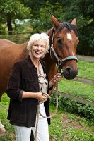 An older woman holding a horse by a bridle