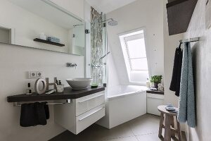 A small, comfortable bathroom with a whirlpool bathtub under a sloping ceiling