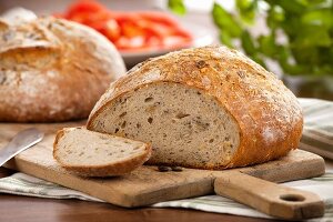 A partly sliced loaf of bread on a chopping board