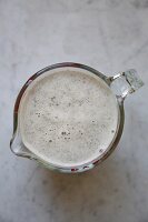 Fresh hemp milk made from roasted, organic hemp sees in a glass jug on a marble surface