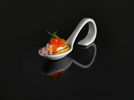 A buckwheat blini and keta caviar on a tasting spoon