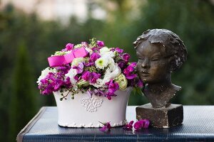 Romantische Blumendekoration mit Frauenbüste auf Vintage Koffer im Freien