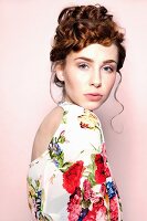 Young woman with curly pinned-up hairdo wearing floral dress