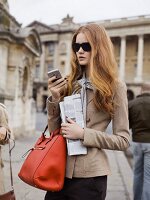 A young woman wearing a sand-coloured blazer with a smart phone