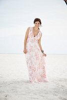 A brunette woman on a beach wearing a long summer dress