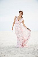 A brunette woman on a beach wearing a long summer dress