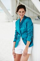 A young brunette woman wearing white shorts and turquoise blazer