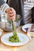 Linguine mit Nudelzange auf Teller servieren