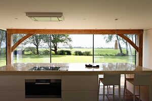 Blick über freistehende Küchentheke durch Panoramafront auf grüne Landschaft